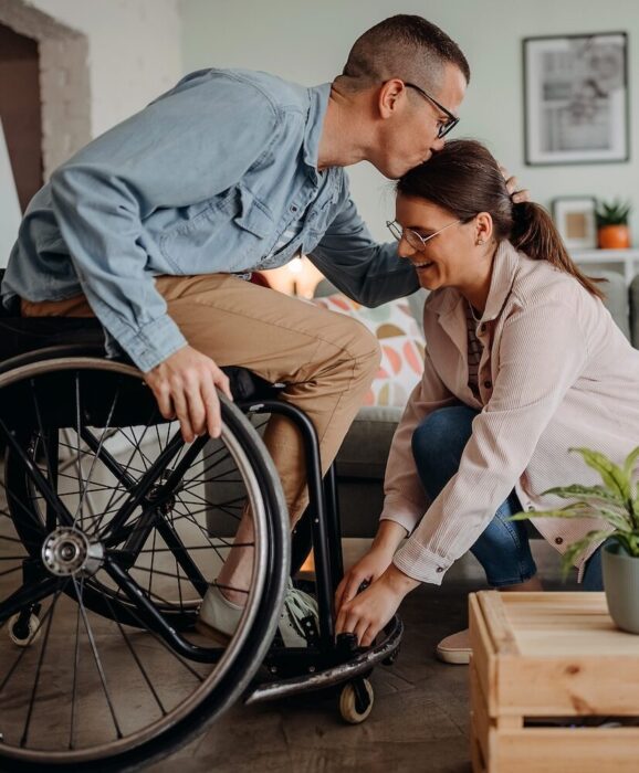 Person in Wheelcare kissing partner on forehead aspect ratio 303 367 3