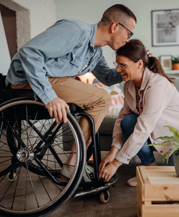 Person in Wheelcare kissing partner on forehead aspect ratio 303 367